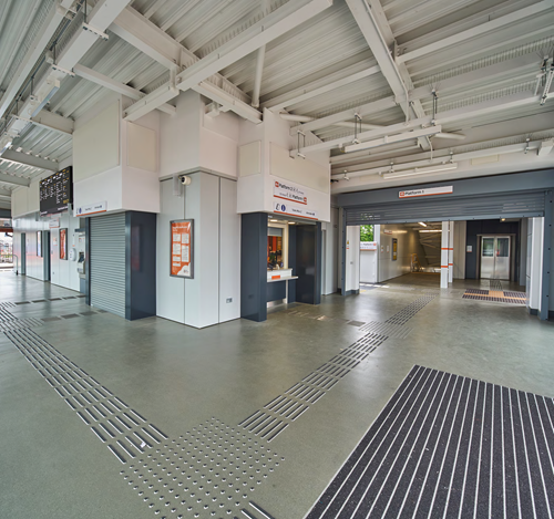 A photo taken inside the station building at Perry Barr railway station, with the ticket office and stairs and lifts down to one of the platforms in shot